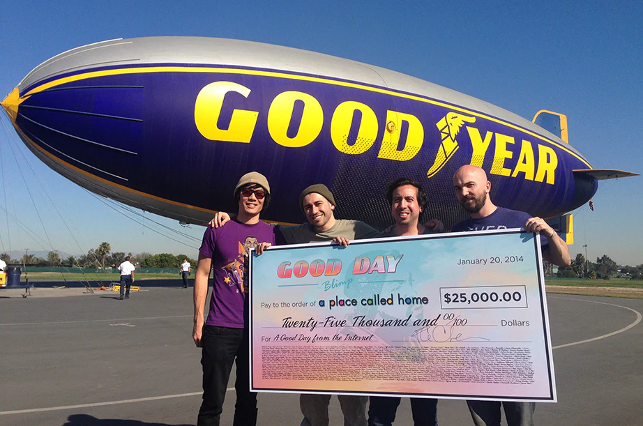 The team presenting the $25,000 check under the blimp